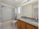 Well-lit bathroom with a granite-topped vanity, bathtub, and tiled floor at 1111 Liberty Hall Dr, Kissimmee, FL 34746