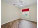 Bedroom with wood-look vinyl flooring, neutral walls, and window with dark shade at 1111 Liberty Hall Dr, Kissimmee, FL 34746