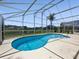 A screened-in kidney shaped pool overlooks a large pond in this beautiful backyard setting with string lights at 1111 Liberty Hall Dr, Kissimmee, FL 34746