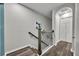Hallway with wood-look floors, decorative wrought iron railing, and arched entry to the bedrooms at 1191 Honey Blossom Dr # D, Orlando, FL 32824