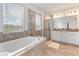 Bright bathroom featuring a soaking tub, walk-in shower, double vanity, and neutral tiling at 15448 Murcott Blossom Blvd, Winter Garden, FL 34787