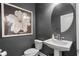 Stylish powder room featuring a pedestal sink, dark gray walls, and art piece at 16412 Good Hearth Blvd, Clermont, FL 34711