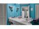 Bright bathroom vanity with white countertop, blue-green accent wall, large mirror, and storage at 165 Durham Pl # 165, Longwood, FL 32779