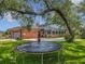 Backyard scene showcasing a trampoline, lush lawn, brick home exterior, and a refreshing pool at 1850 Lakeshore Cir, Longwood, FL 32750