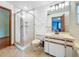 This bathroom features a glass shower, tile floors, white vanity, and stylish lighting at 1850 Lakeshore Cir, Longwood, FL 32750