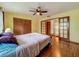 Cozy bedroom with hardwood floors, ceiling fan, closet, and glass doors to the ensuite bathroom at 1850 Lakeshore Cir, Longwood, FL 32750