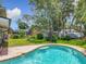 This beautiful backyard features a brick-lined in-ground pool, green grass, and a large tree for shade and privacy at 1850 Lakeshore Cir, Longwood, FL 32750