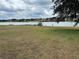 Expansive backyard with lake view, lush green grass, and a few trees offering shade, perfect for outdoor activities at 23717 Milford Dr, Eustis, FL 32736