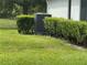 Landscaped side yard featuring well-maintained hedges and an HVAC unit at 23717 Milford Dr, Eustis, FL 32736