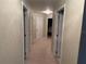 Hallway featuring neutral walls, carpet, multiple doors, and a ceiling fan, providing access to various rooms in the home at 23717 Milford Dr, Eustis, FL 32736