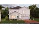 Charming two-story home featuring a manicured lawn, a two car garage, and a welcoming front porch at 2525 Peace Of Mind Ave, Kissimmee, FL 34744