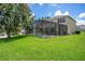 Spacious backyard with a screened-in pool area and lush green lawn, perfect for outdoor activities at 2669 Manesty Ln, Kissimmee, FL 34747