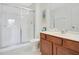 Clean bathroom with a glass-enclosed shower, wooden vanity, and neutral tile flooring at 2669 Manesty Ln, Kissimmee, FL 34747