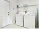 Well-lit laundry room with washer, dryer, and storage shelving at 2669 Manesty Ln, Kissimmee, FL 34747