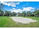 Community sand volleyball court surrounded by green grass and mature palm trees under sunny skies at 2669 Manesty Ln, Kissimmee, FL 34747