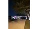 Night view of house exterior with professional landscape lighting, mature trees, and a long driveway at 2919 Foraker Way, Kissimmee, FL 34758