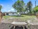 A large backyard featuring a mature tree and an aged stone bench, enclosed by a wooden fence for privacy at 3321 Mahalia Pl, Orlando, FL 32805