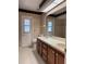 Well-lit bathroom featuring a double sink vanity, white tiled floors, and a door to the exterior at 3917 Lake Mira Dr, Orlando, FL 32817