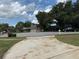 Spacious driveway leading to a charming home with lush landscaping and mature trees on a partially cloudy day at 3917 Lake Mira Dr, Orlando, FL 32817