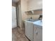 Well-lit laundry room featuring washer, dryer, laundry sink and tiled floor with shelves for storage at 3917 Lake Mira Dr, Orlando, FL 32817