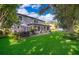 Large backyard with a well-maintained lawn, a patio, trees, and a home with many windows at 394 Baymoor Way, Lake Mary, FL 32746