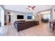 Open-concept living room with wood-look tile floors, neutral paint, ceiling fan, and large brown leather sectional couch at 394 Baymoor Way, Lake Mary, FL 32746