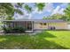 Exterior shot of the home with screened-in patio and generous green space in the backyard at 4800 Reginald Rd, Orlando, FL 32829