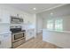 Open kitchen area boasts stainless steel appliances and connects to a dining space with light wood flooring at 4800 Reginald Rd, Orlando, FL 32829
