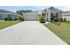 Expansive concrete driveway leading to a grey-toned home with a matching garage door and manicured front yard at 584 S Andrea Cir, Haines City, FL 33844