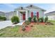 Charming single-story home with a red front door, grey siding, and a well-maintained lawn with tidy landscaping at 584 S Andrea Cir, Haines City, FL 33844