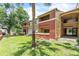 Multi-story building with red and tan exterior, balconies, and green grass with palm trees at 664 Kenwick Cir # 104, Casselberry, FL 32707
