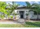 Charming home entrance with tropical landscaping, including palm trees, leading up to a modern, decorative front door at 6805 Barby Ln, Belle Isle, FL 32812