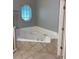 Corner garden tub situated below an angular window in a neutral tiled bathroom at 7924 Bridgestone Dr, Orlando, FL 32835
