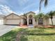 Charming single-story home featuring a well-manicured lawn, beautiful palm trees, and a welcoming front entrance at 14014 Spruce Creek Ln, Orlando, FL 32828