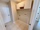 Bright laundry room with tiled floors, overhead cabinets, and a door to the adjacent rooms at 14014 Spruce Creek Ln, Orlando, FL 32828