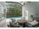 Covered patio area with comfortable seating, grill, and view of the screened-in pool at 10064 River Glen Ct, Orlando, FL 32825