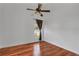 A minimalist bedroom with hardwood floors, a ceiling fan, and a window with brown curtains at 12713 Pine Arbor Dr, Clermont, FL 34711