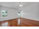 Empty bedroom with hardwood floors, ceiling fan and well-lit by two large windows at 12713 Pine Arbor Dr, Clermont, FL 34711