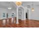 Spacious living room featuring hardwood floors, decorative columns, and elegant chandeliers at 12713 Pine Arbor Dr, Clermont, FL 34711