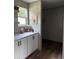 Counter with upper and lower white cabinets, black hardware, and open window offer charm and storage at 1349 Nw 109 Ave, Ocala, FL 34482