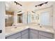 Bathroom featuring dual sinks, light grey cabinetry, and a shower with glass doors at 14063 Ithaca Way, Orlando, FL 32826