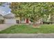 Charming single-story home featuring a red front door and a large tree providing shade in the front yard at 14063 Ithaca Way, Orlando, FL 32826