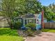 A quaint blue home with brick chimney, surrounded by green lawn and mature trees, offers a welcoming, picturesque setting at 1642 Mount Vernon St, Orlando, FL 32803