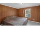 Comfortable bedroom with wood paneled walls and natural light streaming in from the window at 18166 Lynbrook Rd, Orlando, FL 32820