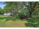 Exterior view of a mobile home on a grassy lot with mature trees and outbuildings at 18166 Lynbrook Rd, Orlando, FL 32820