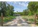 Gated property with a long gravel driveway leading to a charming single-story home surrounded by mature trees at 18166 Lynbrook Rd, Orlando, FL 32820