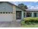 Front entrance featuring stone accents, a two-car garage, and lush landscaping at 3220 Cardigan Ct, Orlando, FL 32812