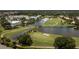 Aerial view of community golf course surrounded by lake and clubhouse at 387 Devon Pl, Lake Mary, FL 32746