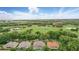 Aerial view of homes and a golf course with lush trees, a pond and nearby commercial buildings at 387 Devon Pl, Lake Mary, FL 32746