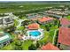 An aerial view of a community pool area, featuring a heart shaped pool, hot tub, and well-manicured lawns amid condo buildings at 426 Bouchelle Dr # 202, New Smyrna Beach, FL 32169